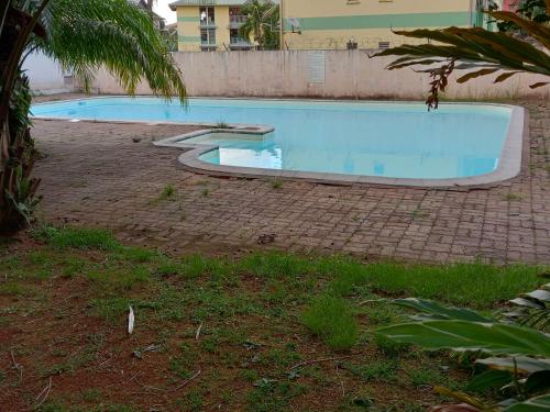 a large swimming pool in a yard with a brick ground at Magnifique T2 meublé avec piscine in Cayenne