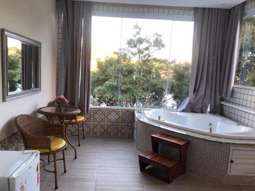a bathroom with a tub and a table and a window at Pousada Paraiso de Igaratá in Igaratá
