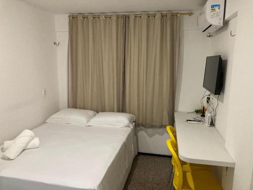 une petite chambre avec un lit et un bureau avec un ordinateur dans l'établissement 104 Apart mobiliado vista mar Praia de Iracema, à Fortaleza