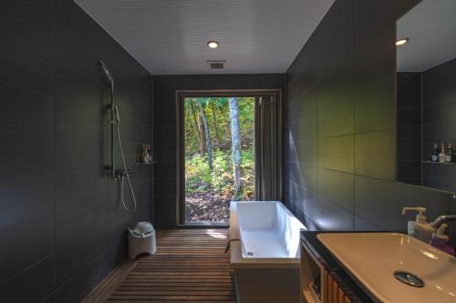a bathroom with a tub and a sink and a window at Phoenix Chalets by HHG in Hakuba