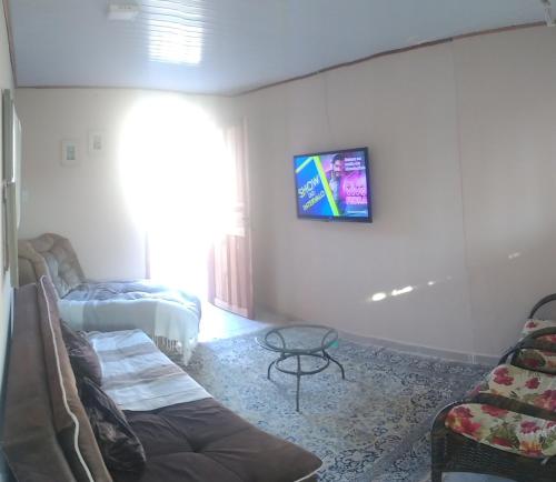 a living room with a couch and a tv on the wall at Casa barreto in Florianópolis
