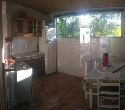 a small kitchen with a table and a refrigerator at Casa barreto in Florianópolis