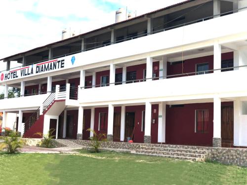 a large white building with a lawn in front of it at Hotel Villa Diamante in Xpujil