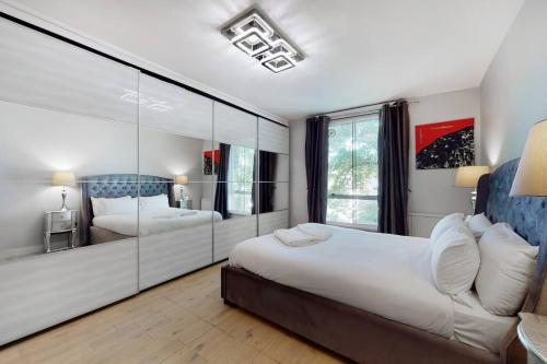 1 dormitorio con 2 camas y pared de espejo en Superb 3 bed flat with balcony in St John's Wood en Londres