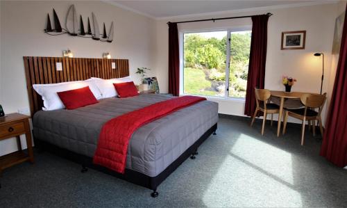 a bedroom with a bed and a table and a window at Labyrinth Gardens Guest House in Takaka