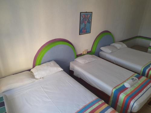 three beds in a room with rainbow frames at Pargos Hotel & Cowork in Puerto Escondido