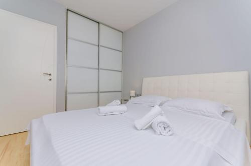 Una cama blanca con sábanas blancas y toallas. en Apartment Rocky, en Trogir