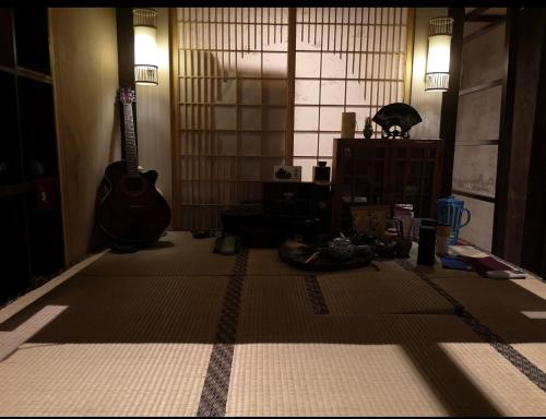 a living room with a guitar and a table at 台甕茶室青年旅館 Tai-Wong Tatami Room Hostel in Tainan
