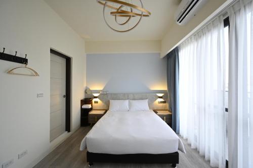 a bedroom with a white bed and a large window at 台南安平 - 理蓄豪宅 - 可加價Ktv及烤肉 in Tainan