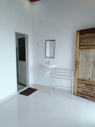 a white bathroom with a sink and a mirror at Bara Village Guest House Bira in Bira