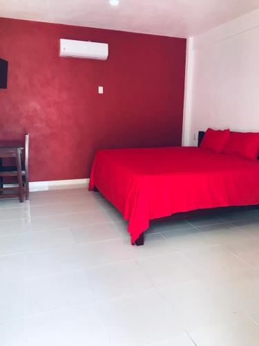 a red bed in a room with a red wall at Hotel Villa Diamante in Xpujil