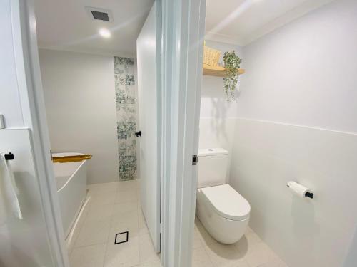 a white bathroom with a toilet and a shower at Nuts About the Bay in Nelson Bay