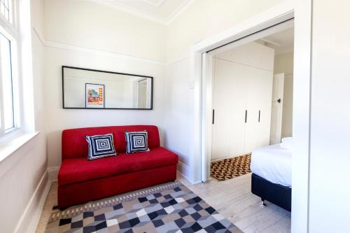 een rode stoel in een slaapkamer met een bed bij Chic Bondi Beach Pad in Sydney