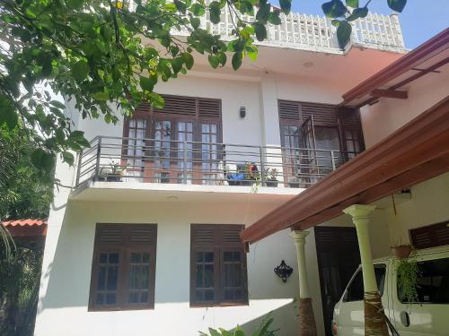 a white house with windows and a balcony at Abinu"s Place in Dickwella