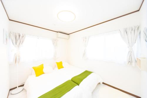 a bedroom with a bed and two windows at Awaji Garden House in Shinmura in Sumoto