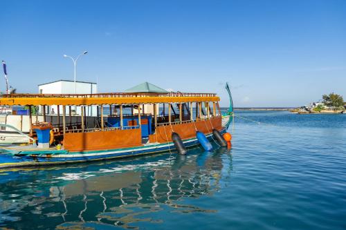 an orange boat is docked in the water at Sky Beach Maldives - Dhiffushi in Dhiffushi