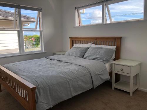 a bedroom with a large bed with two windows at Comfortable Holiday Home at Mt Wellington in Auckland