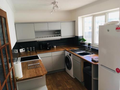 a kitchen with white cabinets and a white refrigerator at Elite Accomm Wolverhampton sleeps 4 long term workers or family comfortably in Shareshill
