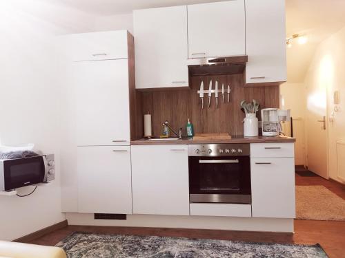 una cocina con armarios blancos y horno negro en Ferienwohnung Cooldog Kuschelnest, en Imst