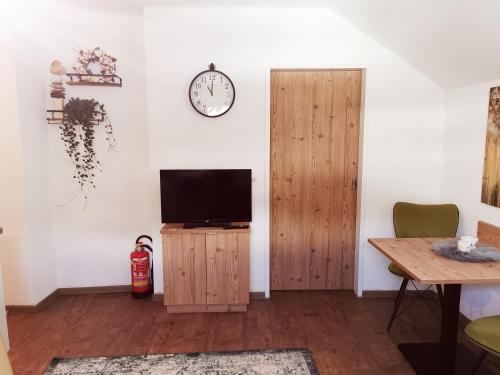 Ferienwohnung Cooldog Kuschelnest في امست: غرفة معيشة فيها تلفزيون وساعة على الحائط