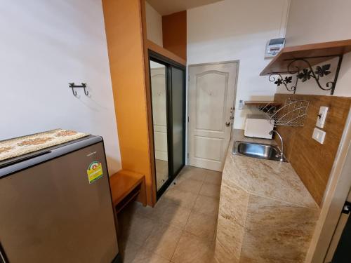 a small kitchen with a sink and a refrigerator at Kireeya Villa in Phetchaburi
