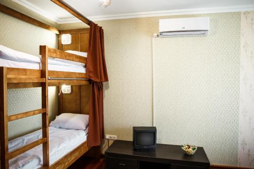 a room with bunk beds with a desk and a television at Sweet Home Hostel in Chernivtsi