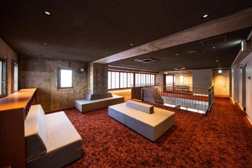 a living room with two couches and a staircase at AMANEK Inn Beppu in Beppu