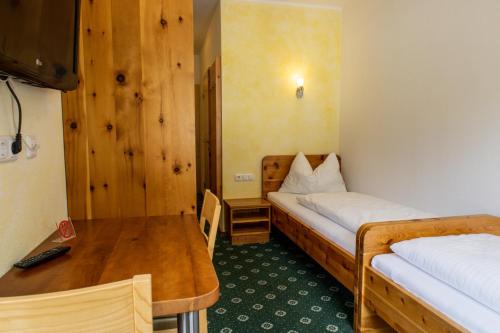 a room with two beds and a wooden table at Gasthof Dreiländereck in Schwarzenberg am Bohmerwald
