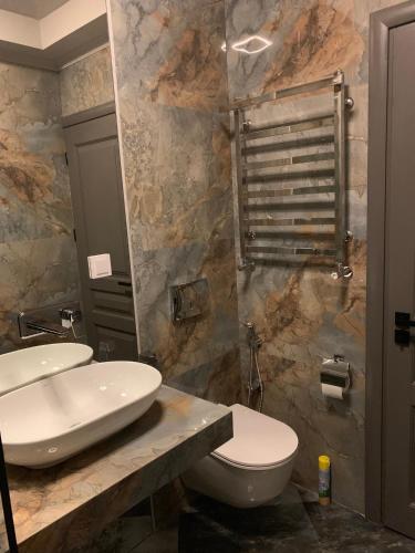 a bathroom with a white toilet and a sink at Apartments Lux in city center Lviv in Lviv