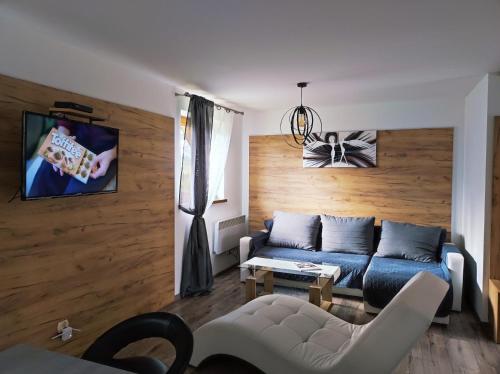 - un salon avec un canapé bleu et un mur en bois dans l'établissement Gniewnik, à Białka Tatrzańska