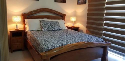 a bedroom with a wooden bed with two lamps on tables at PICO DE LORO RESORT CONDOTEL in Nasugbu