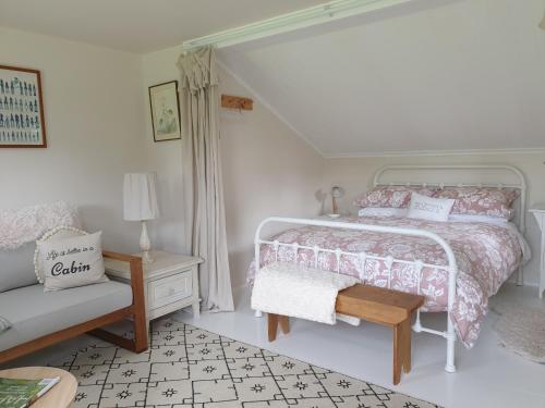 a white bedroom with a bed and a chair at Cabins on Tudor bed & breakfast in Motueka