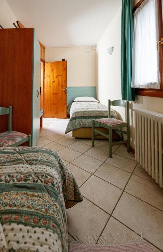 a bedroom with two beds and a tiled floor at Hotel Villa Rina in Bormio