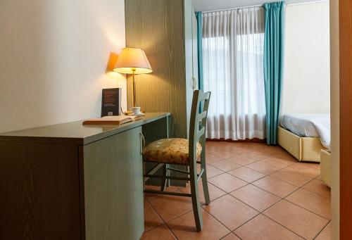 a hotel room with a desk with a lamp and a chair at Hotel Villa Rina in Bormio