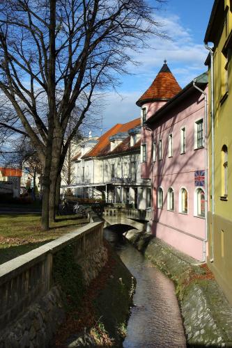 a bridge over a river next to a pink building at Aqua Hotel Termál in Mosonmagyaróvár