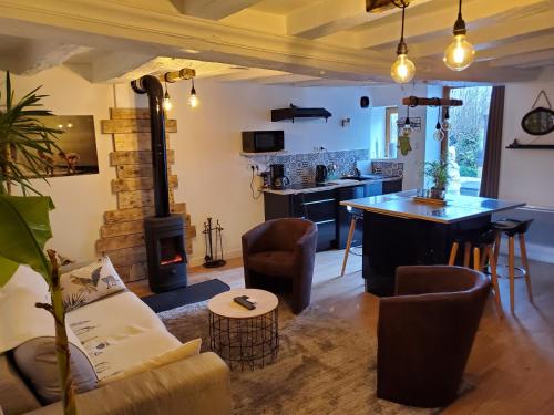 a living room with a couch and a stove at Le Cottage Belmontais, maison individuelle, vue panoramique sur la rivière in Beaumont-sur-Sarthe