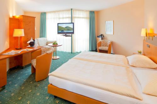 ein Hotelzimmer mit einem Bett und einem Schreibtisch in der Unterkunft Ringhotel Roggenland in Waldeck