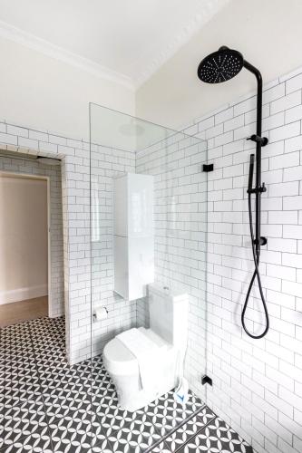 a white bathroom with a toilet and a shower at Chic Bondi Beach Pad in Sydney