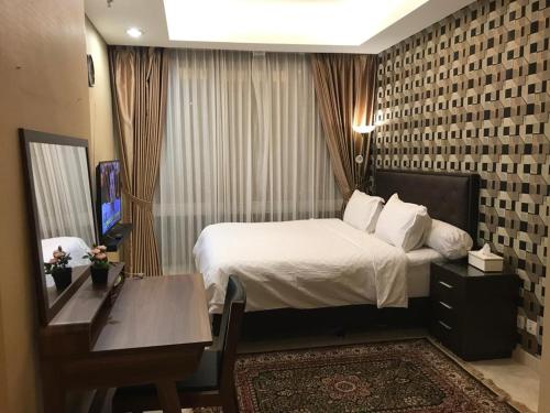 ジャカルタにあるLuxury 2 BR Suite at The Grove-Masterpiece, Epicentrumのベッドとデスクが備わるホテルルームです。