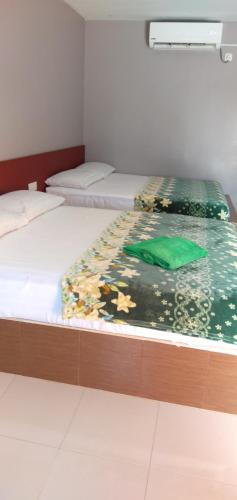 two twin beds in a room with at Inapan Aishah in Pantai Cenang