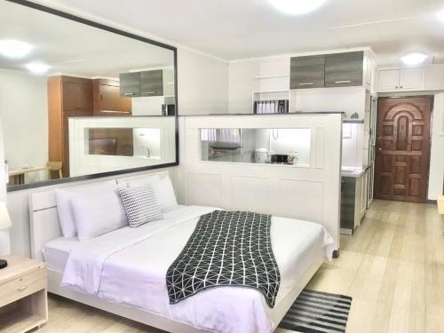 a bedroom with a large white bed and a kitchen at Chill Chill at Nimman in Chiang Mai