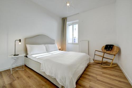 a white bedroom with a bed and a chair at MIRALAGO - Garda Leisure in Salò