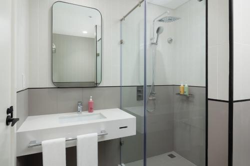 a bathroom with a sink and a shower with a mirror at Rove Expo City in Dubai