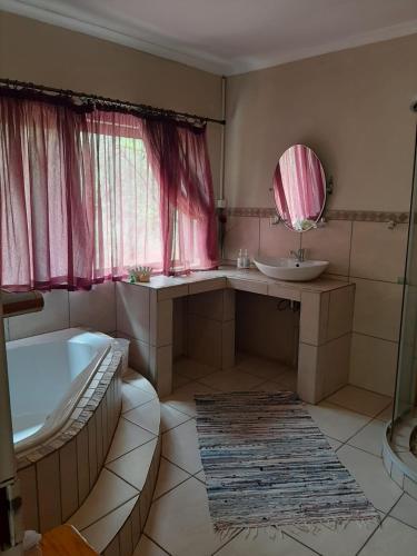 a bathroom with a tub and a sink and a mirror at Aloes Bush Stay in Hoedspruit
