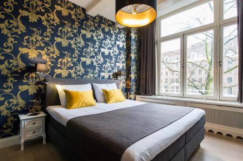 Grand Canal Boutique Hotel في أمستردام: غرفة نوم بسرير وورق جدران زرقاء وذهبية