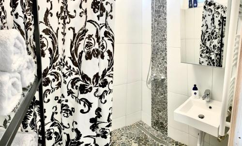a bathroom with a black and white shower curtain and a sink at K1 Panoramic apartment in Szekszárd