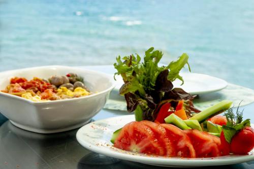 a table with plates of food and a bowl of salad at Assos Kartal Yuvasi Hotel in Sazlı