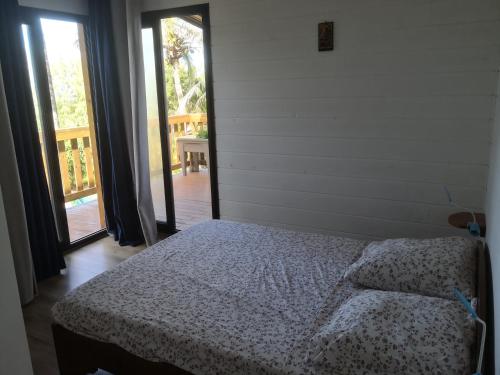 ein Schlafzimmer mit einem Bett in einem Zimmer mit Glasschiebetüren in der Unterkunft Ti Kaz en l'R in Saint-Leu