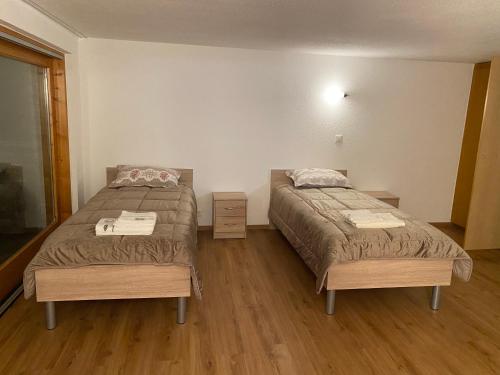 2 Betten in einem Zimmer mit Holzböden in der Unterkunft chalet à diolly in Savièse