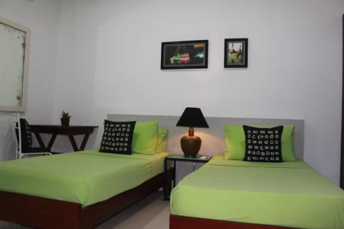 two beds in a room with green sheets at The Classic-hostel-apt-deluxe in Weligama